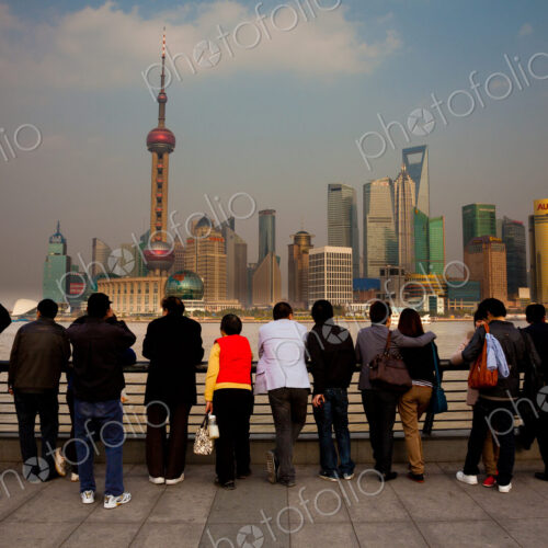 A row of people looking at the Shanghai Pudong skyline, including the Oriental Pearl…