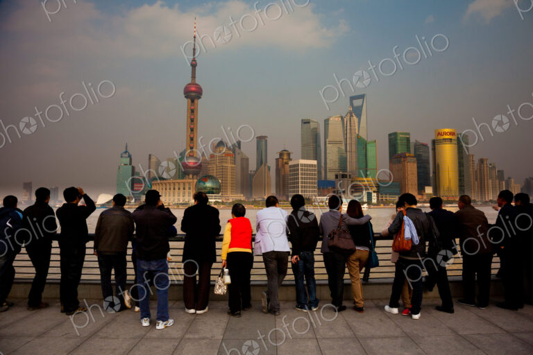 A row of people looking at the Shanghai Pudong skyline, including the Oriental Pearl…