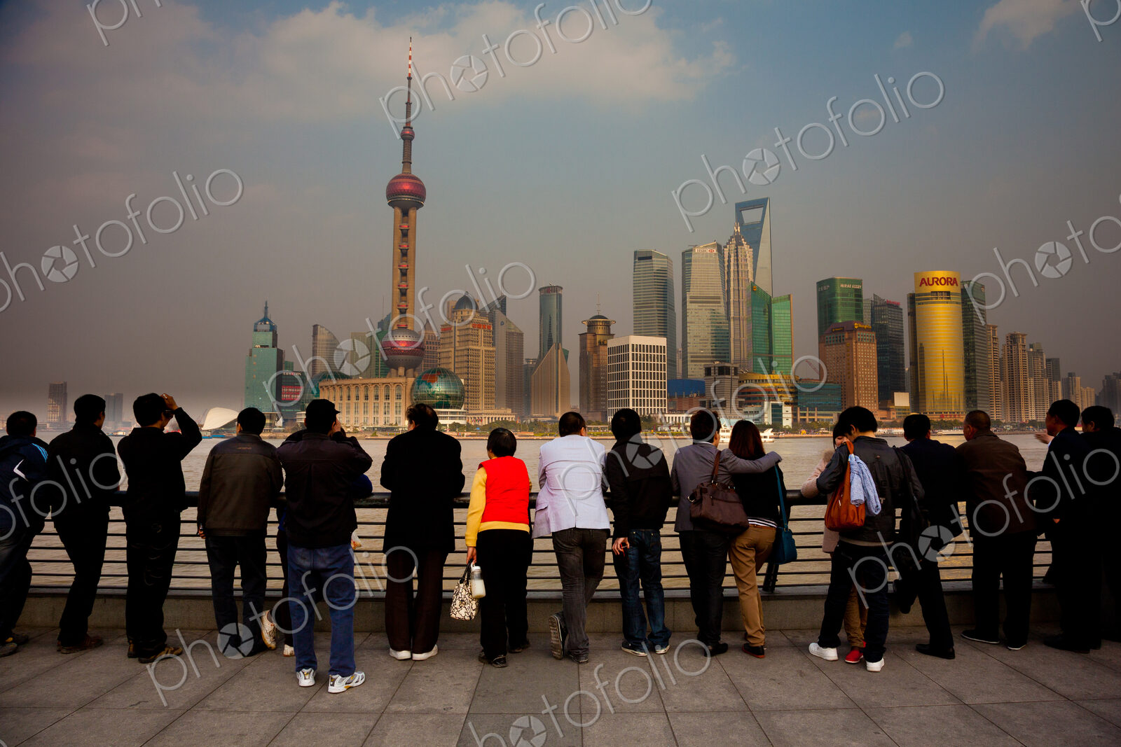 A row of people looking at the Shanghai Pudong skyline, including the Oriental Pearl…