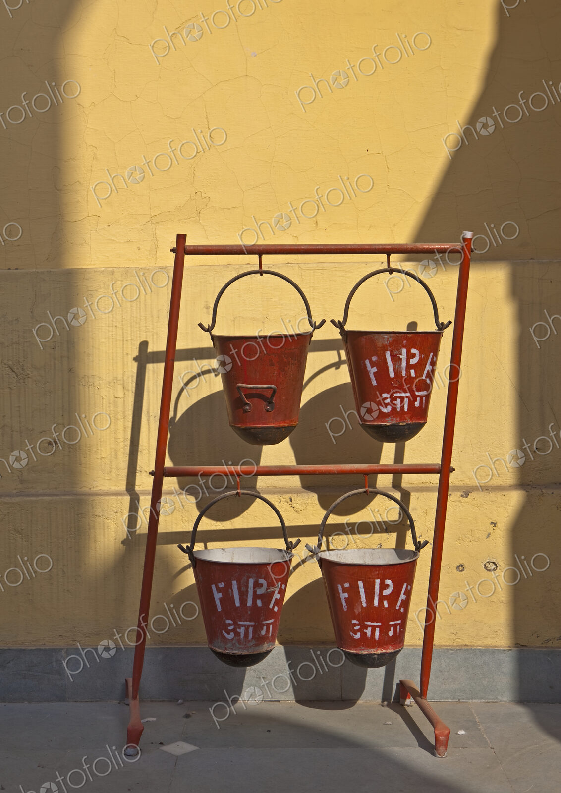 A row of red fire sand buckets on a frame outside a building, the Birla temple in New…