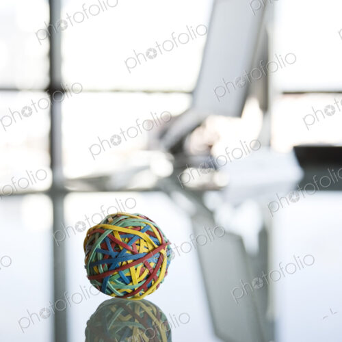 A rubber band ball sitting on a reflective desk in an office. A rubber band ball sitting on a reflective desk in an office.