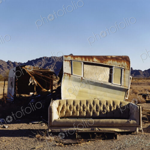 A ruined caravan, with rusting roof, a shelter, and a sofa. A ruined caravan, with rusting roof, a shelter, and a sofa.