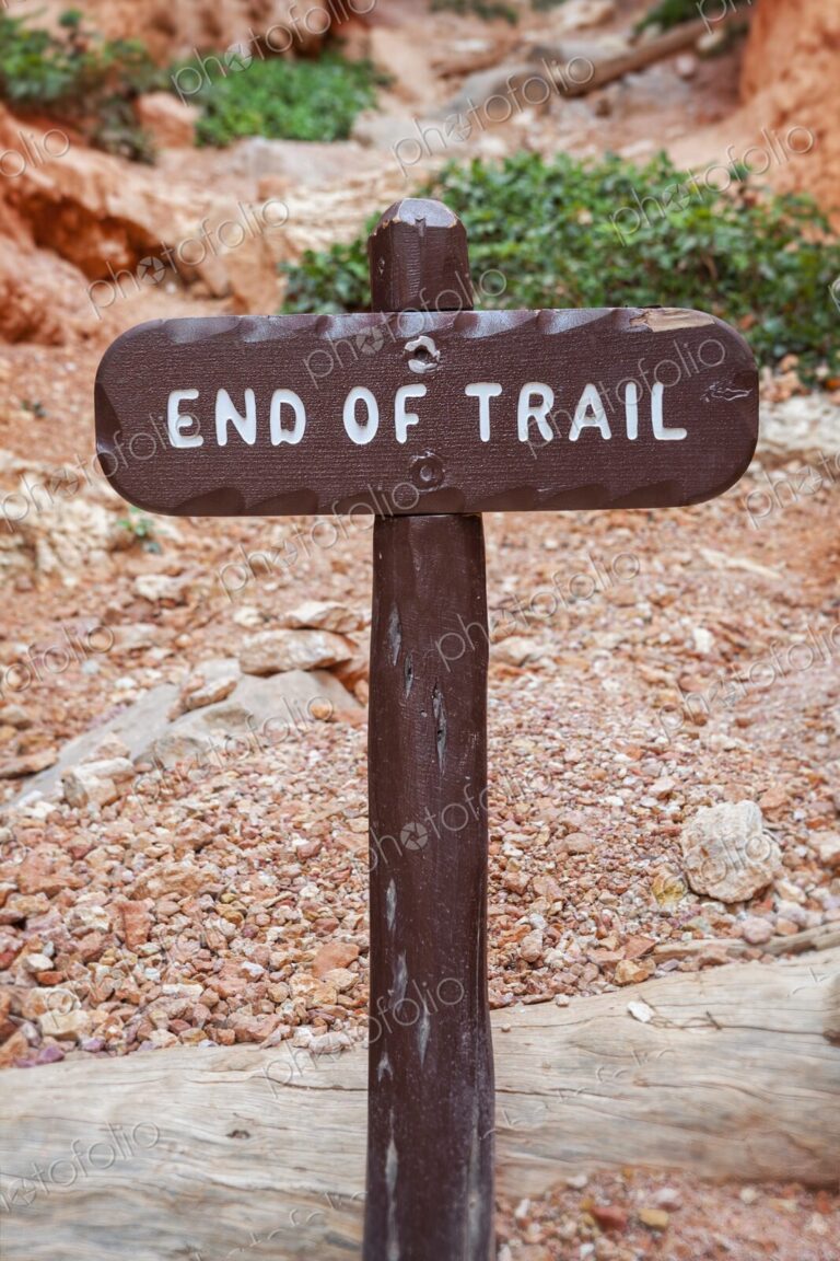 A rustic wooden 'End of Trail' sign marks the conclusion of a hiking path in Bryce…