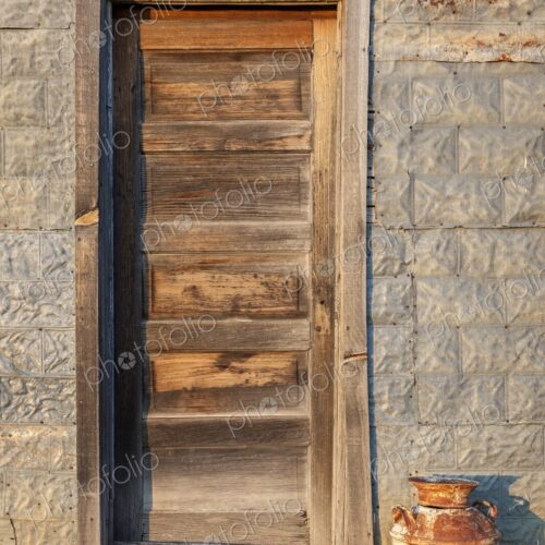 A rustic wooden door and old milk can catch warm evening light on a prairie building… A rustic wooden door and old milk can catch warm evening light on a prairie building…