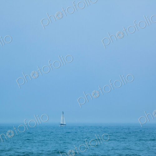 A sailboat on the ocean, view over water.