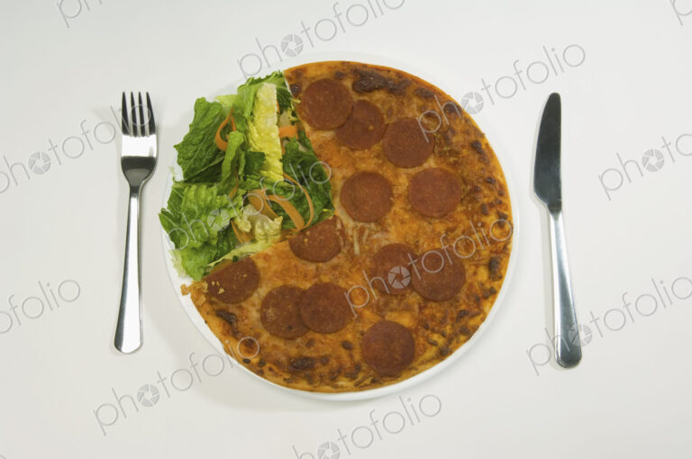 A salami pizza and salad on a plate.