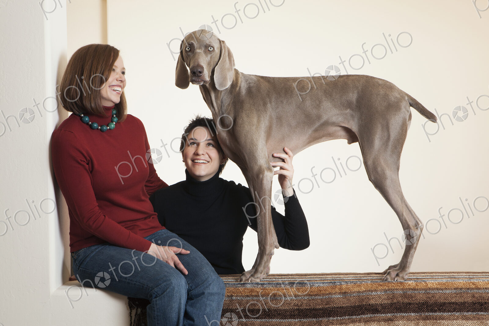 A same sex couple, two women posing with their Weimaraner pedigree dog.
