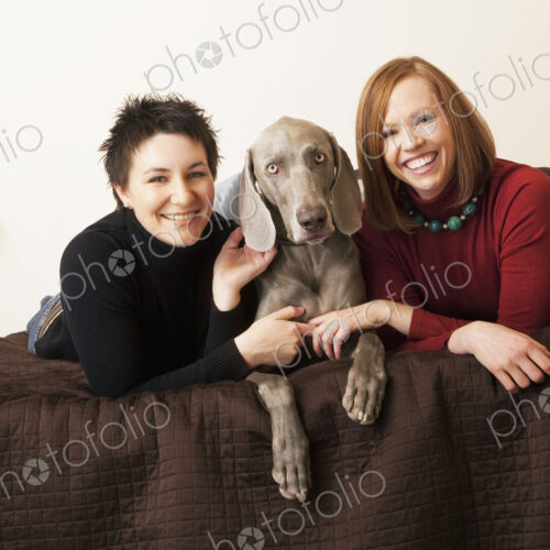 A same sex couple, two women with their Weimaranar pedigree dog between them. A same sex couple, two women with their Weimaranar pedigree dog between them.