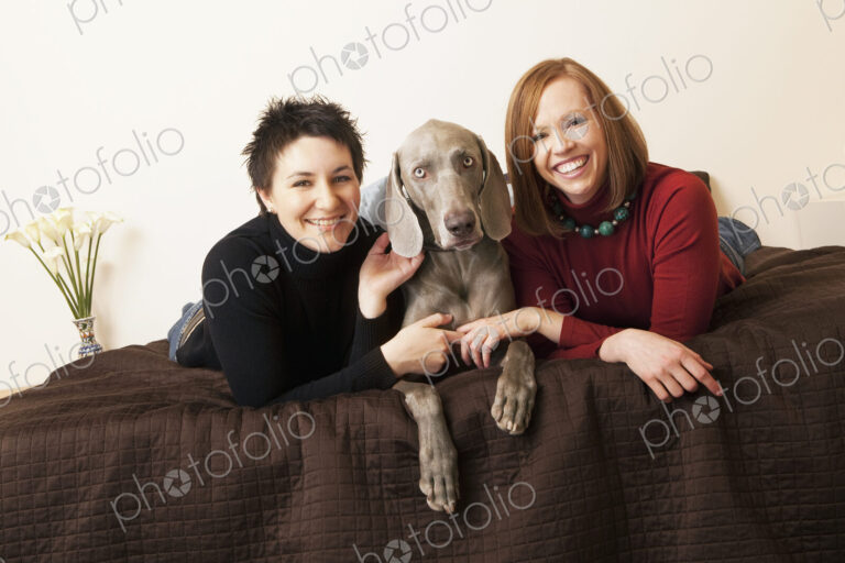 A same sex couple, two women with their Weimaranar pedigree dog between them.