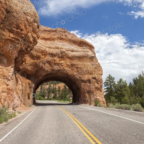 A scenic tunnel carved through red rock along Highway 12 near Bryce Canyon, Utah. A…
