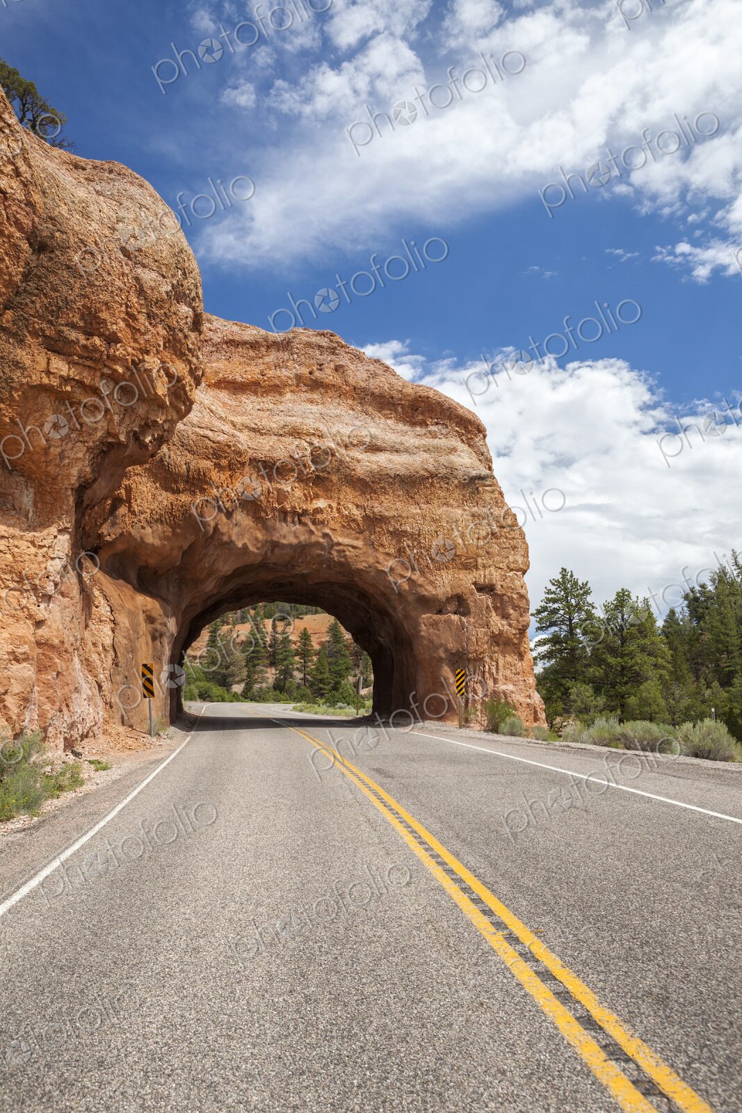 A scenic tunnel carved through red rock along Highway 12 near Bryce Canyon, Utah. A…