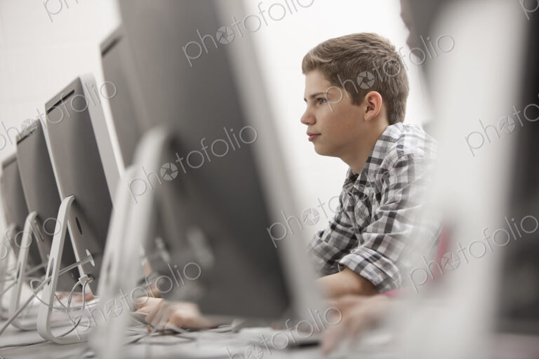 A school room, computer laboratory or lab with rows of computer monitors and seating.…