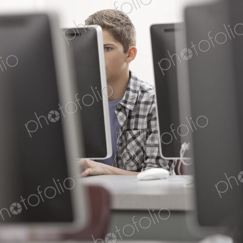 A school room, computer laboratory or lab with rows of computer monitors and seating.…