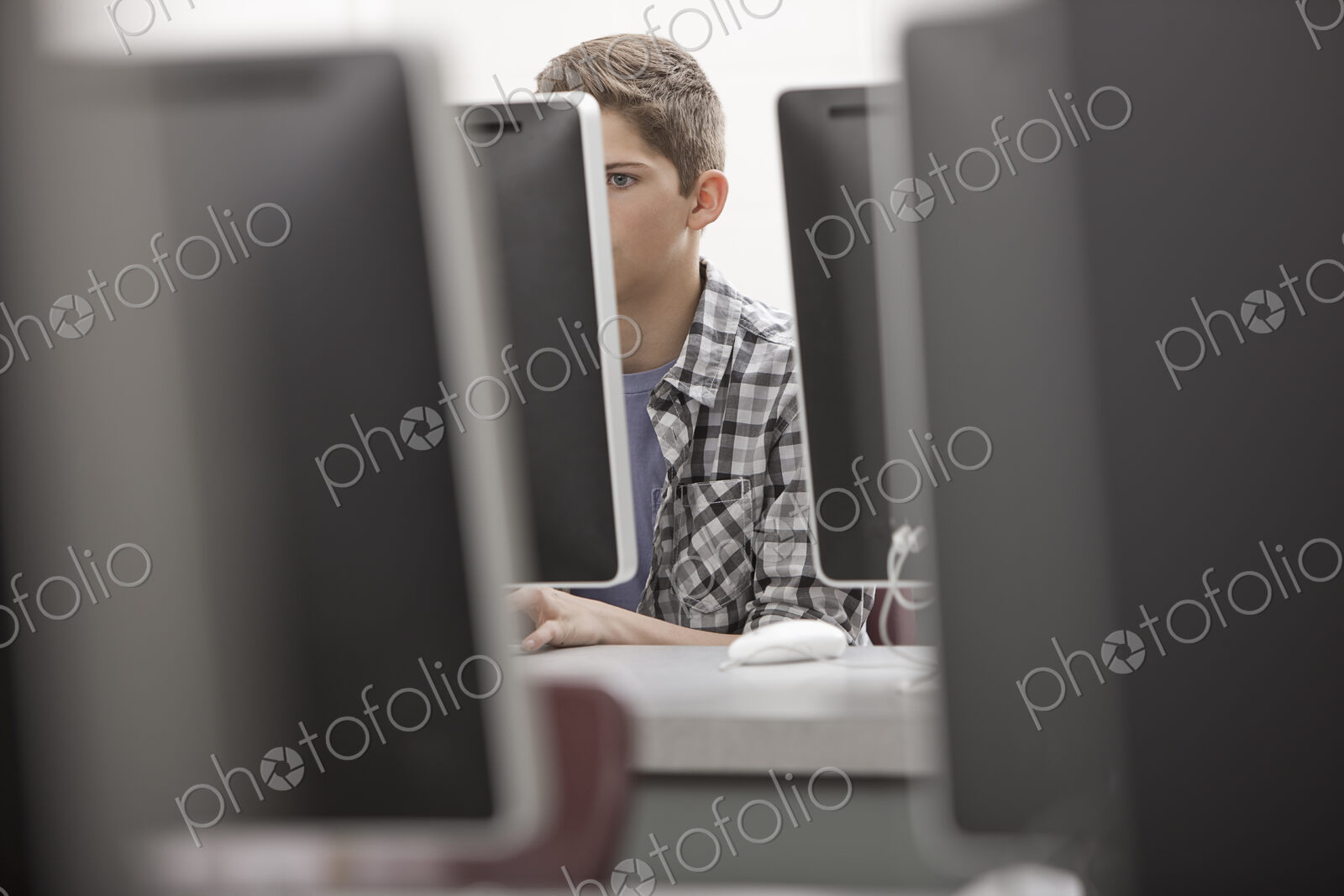 A school room, computer laboratory or lab with rows of computer monitors and seating.…
