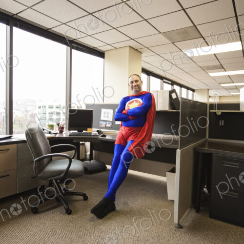 A self satisfied caucasian office super hero in his office cubicle.