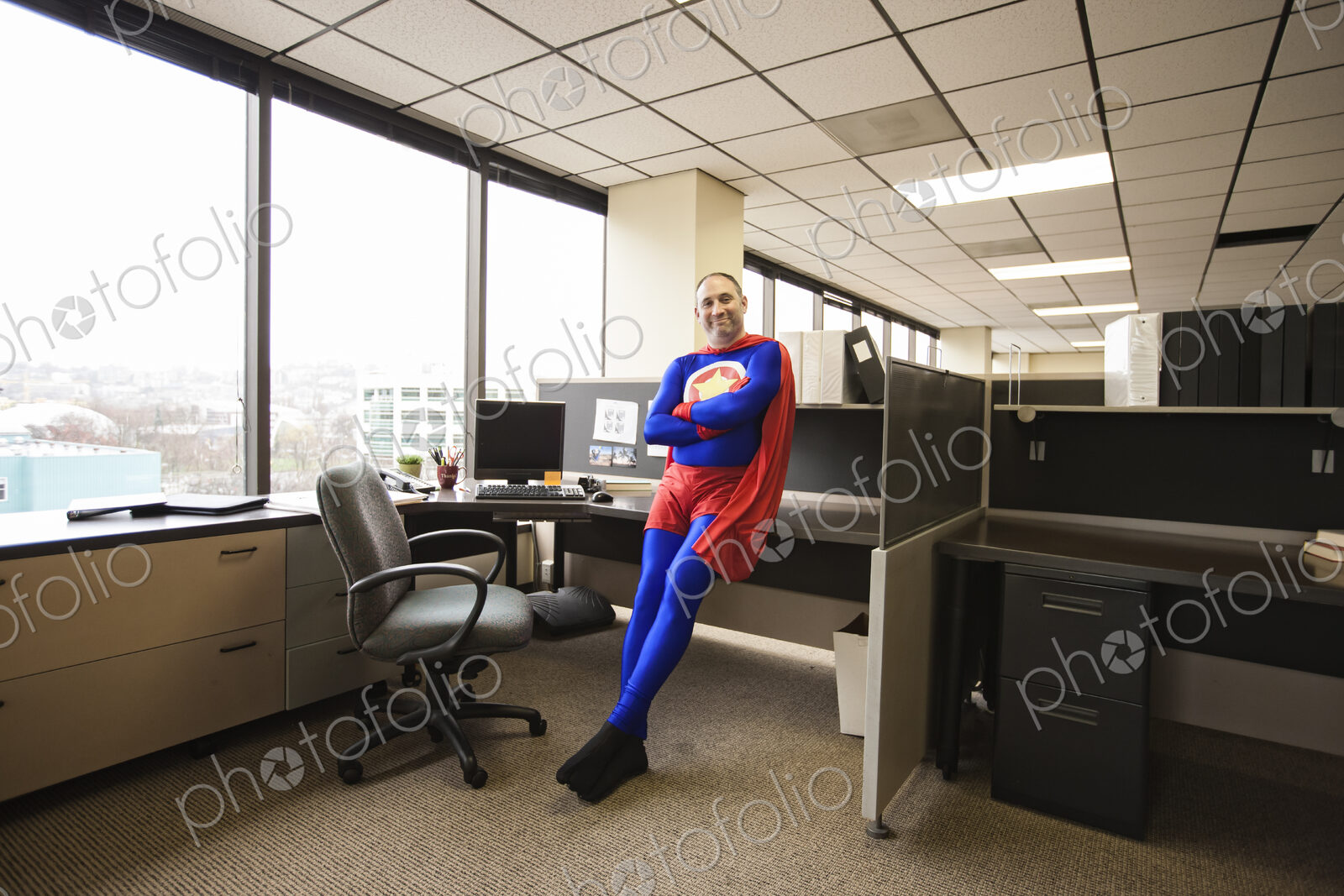 A self satisfied caucasian office super hero in his office cubicle.