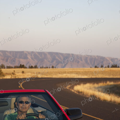 A senior Hispanic man at the wheel of his convertible sports car. A senior Hispanic man at the wheel of his convertible sports car.