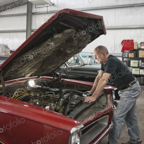 A senior car mechanic working on a car in his repair shop.