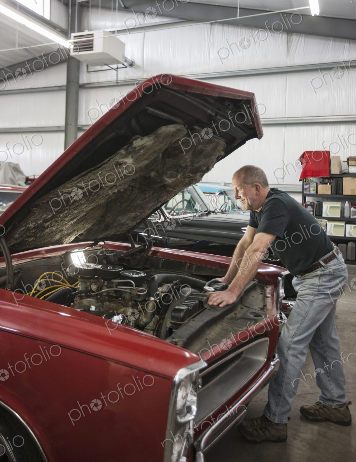 A senior car mechanic working on a car in his repair shop.