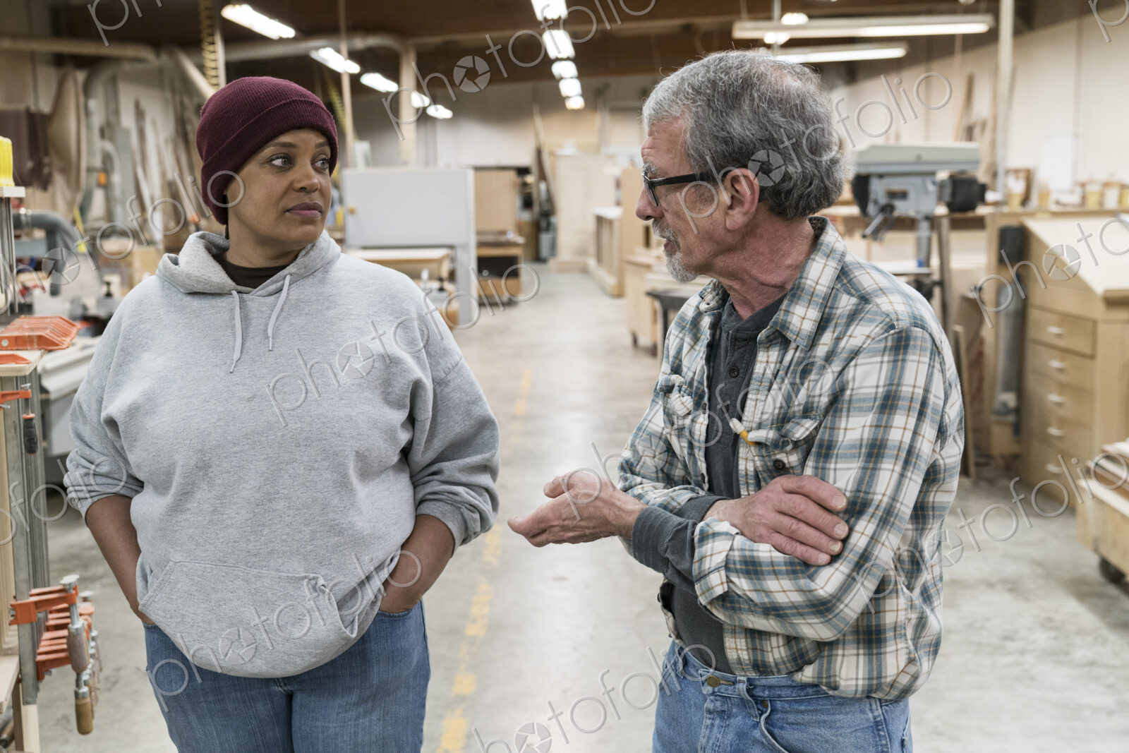 A senior causian male carpenter and a Black female carpenter discussion a project in a…