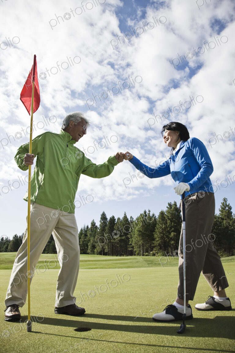 A senior couple doing a fist bump after making putt on a green.