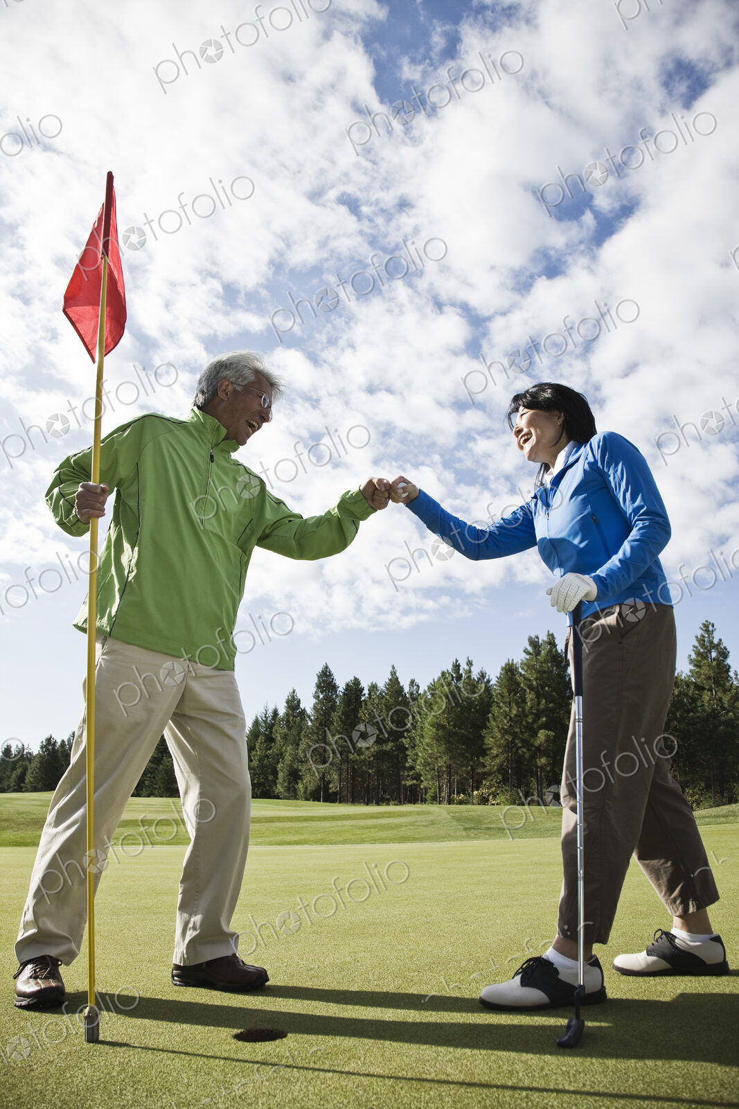 A senior couple doing a fist bump after making putt on a green.