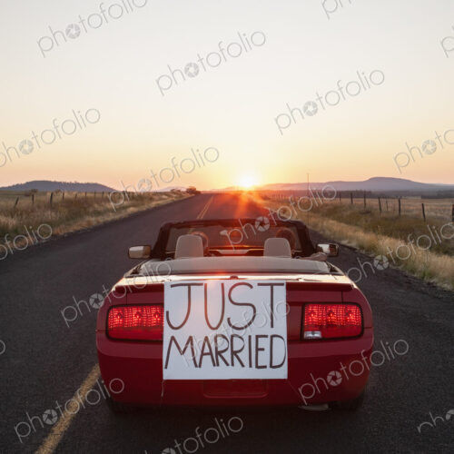 A senior couple "just married" riding in a convertible sports car in eastern…