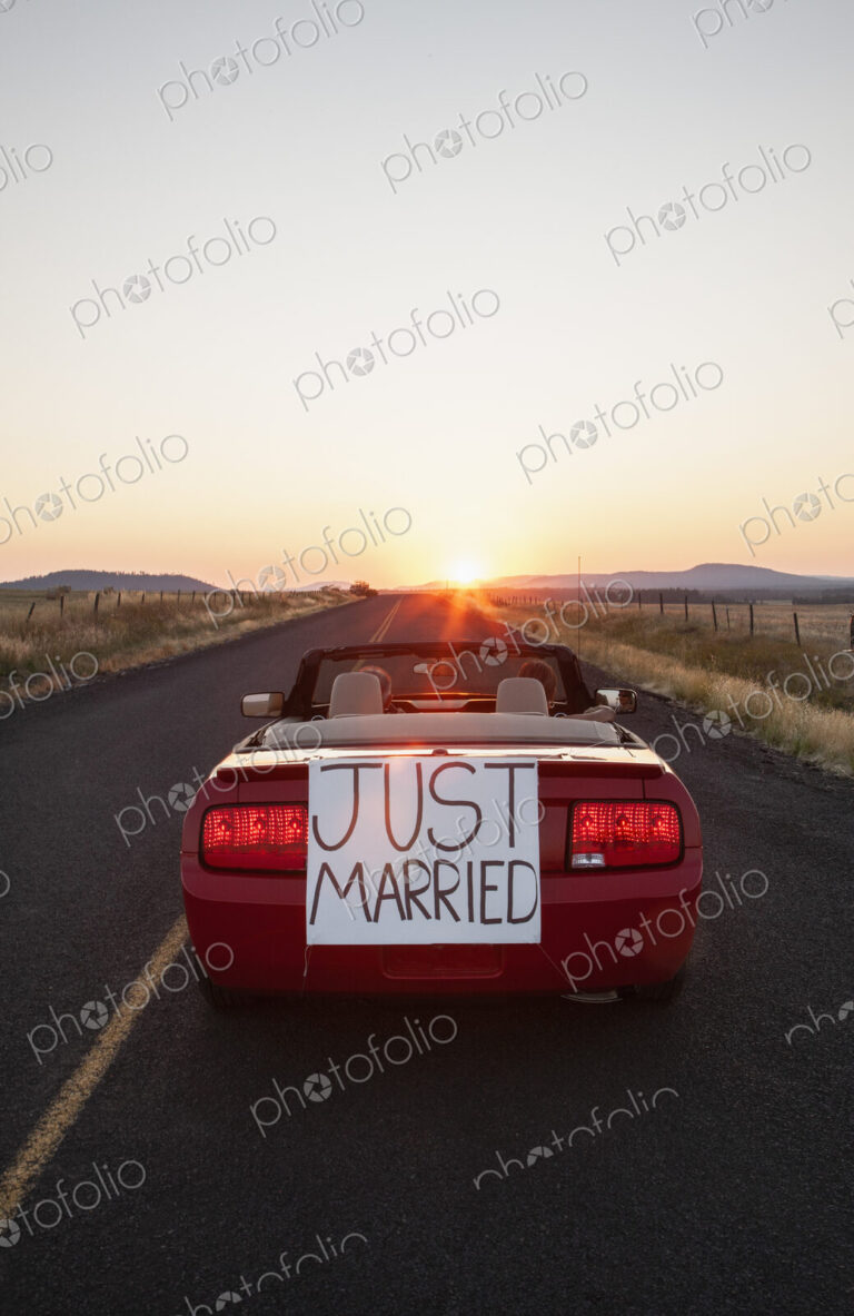 A senior couple "just married" riding in a convertible sports car in eastern…