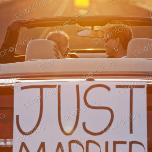 A senior couple "just married" riding in a convertible sports car in eastern…