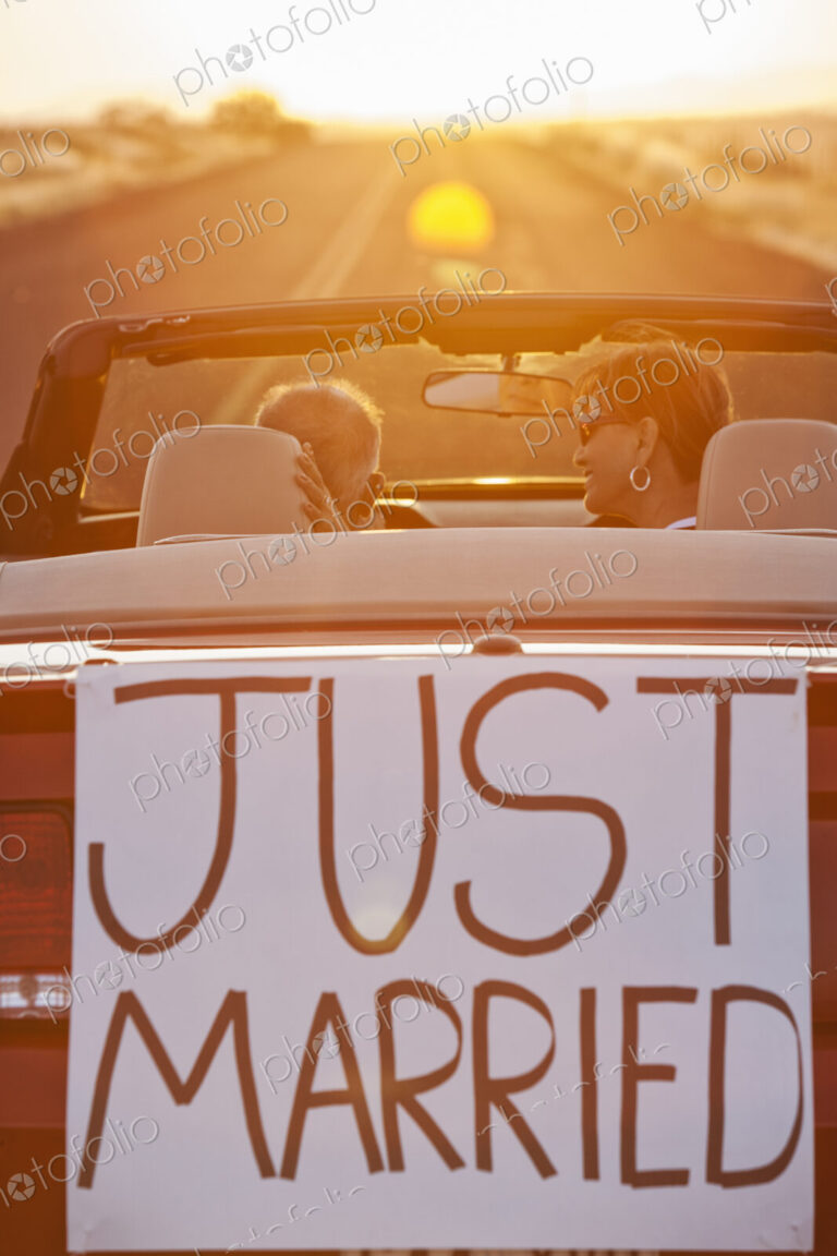A senior couple "just married" riding in a convertible sports car in eastern…