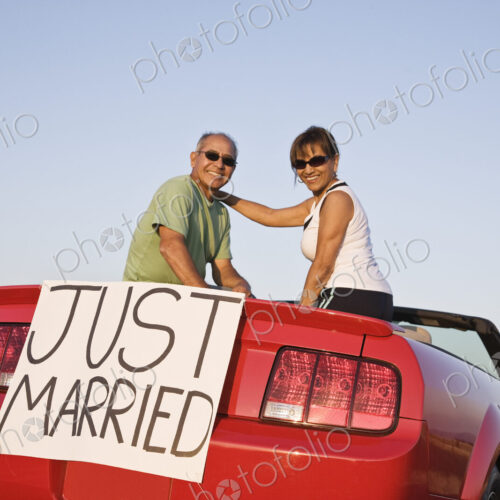A senior couple "just married" sitting in a convertible sports car in eastern…