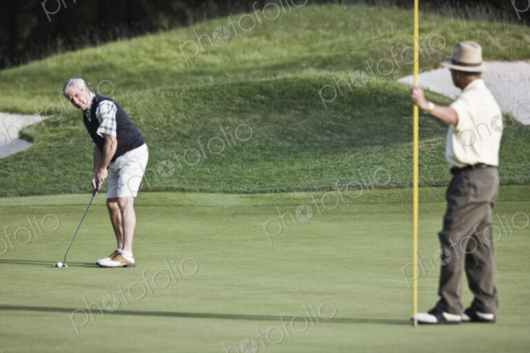 A senior golfer about to attempt a putt on a golf course.