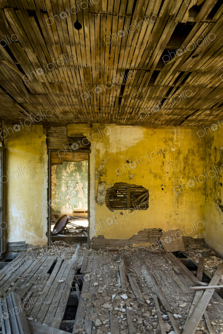A shell of a building, a derelict house interior, exposed timbers and peeling…