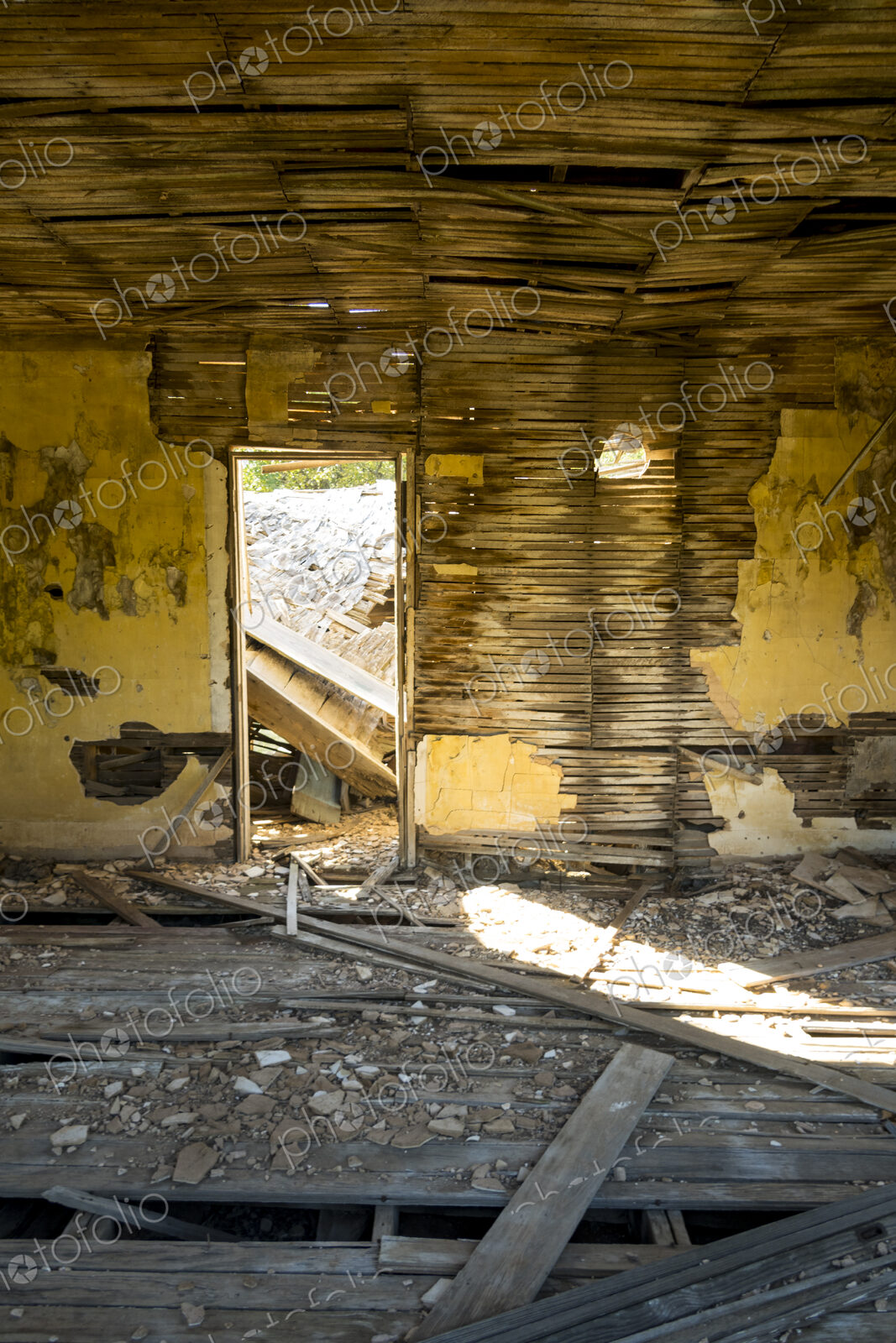 A shell of a building, a derelict house interior, exposed timbers and peeling…