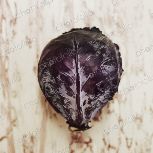 A shot of a head of red cabbage on a wooden surface, seen from above.