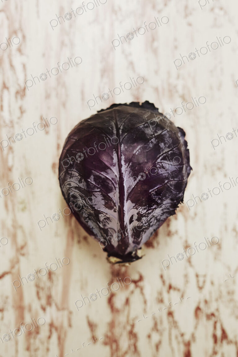 A shot of a head of red cabbage on a wooden surface, seen from above.