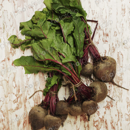 A shot of bundles of beets on a wooden surface, seen from above.
