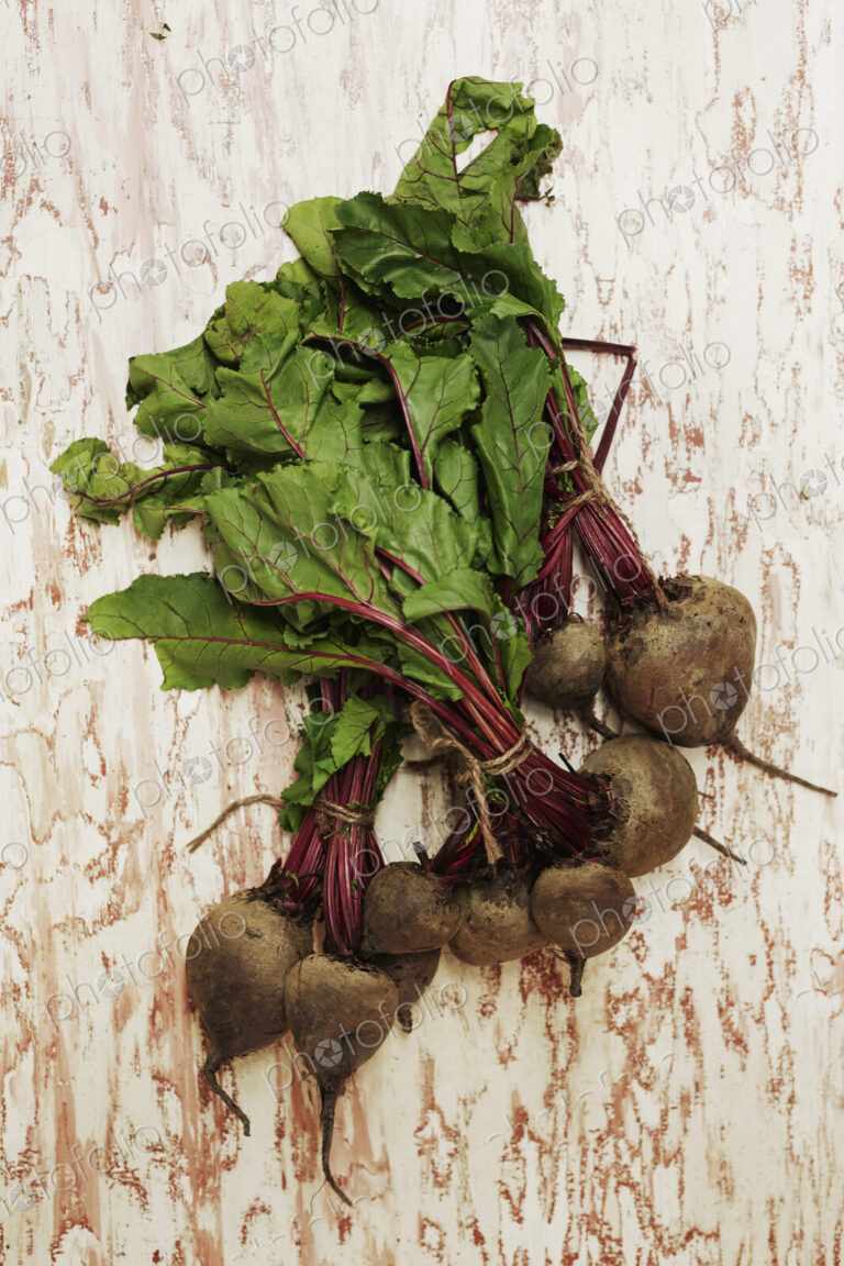 A shot of bundles of beets on a wooden surface, seen from above.