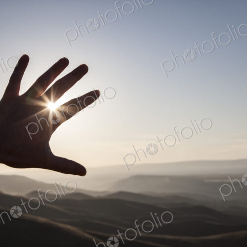 A silhouette of a person's hand in the sun