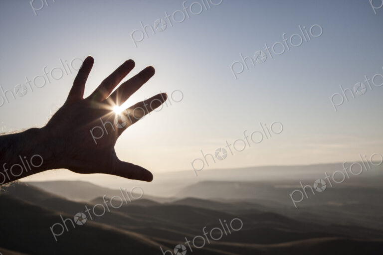 A silhouette of a person's hand in the sun