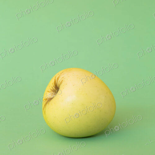 A single Golden Delicious apple on a green background. A single Golden Delicious apple on a green background.