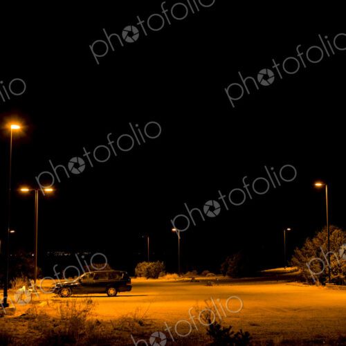 A single car parked under lights in a car park in Santa Fe and night.