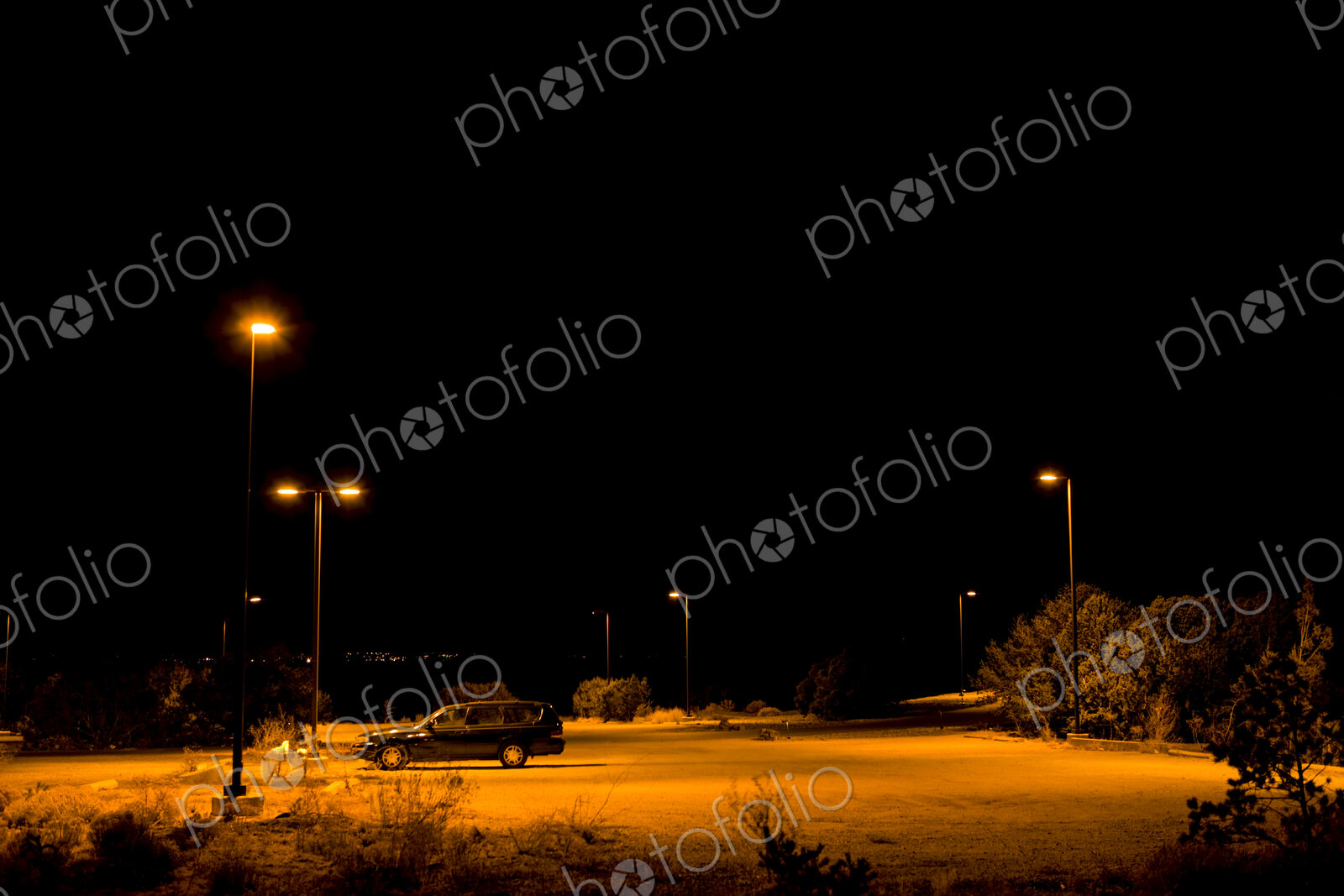A single car parked under lights in a car park in Santa Fe and night.