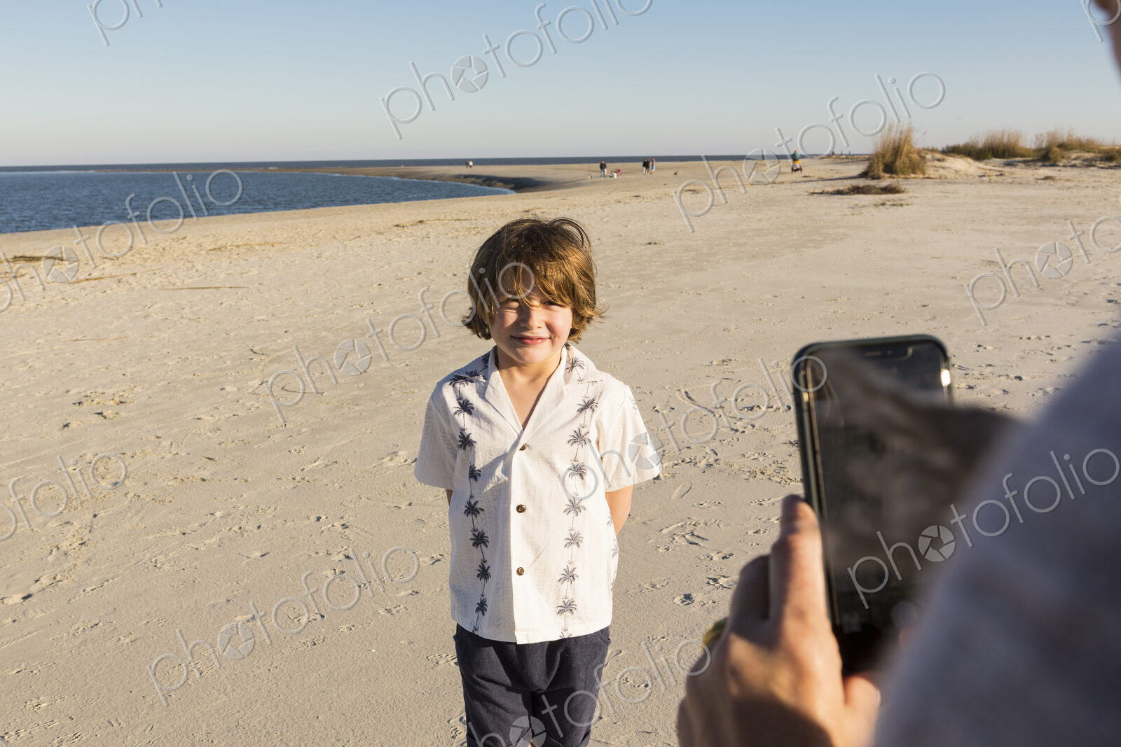 A six year old boy being photographed by his mother at the beach