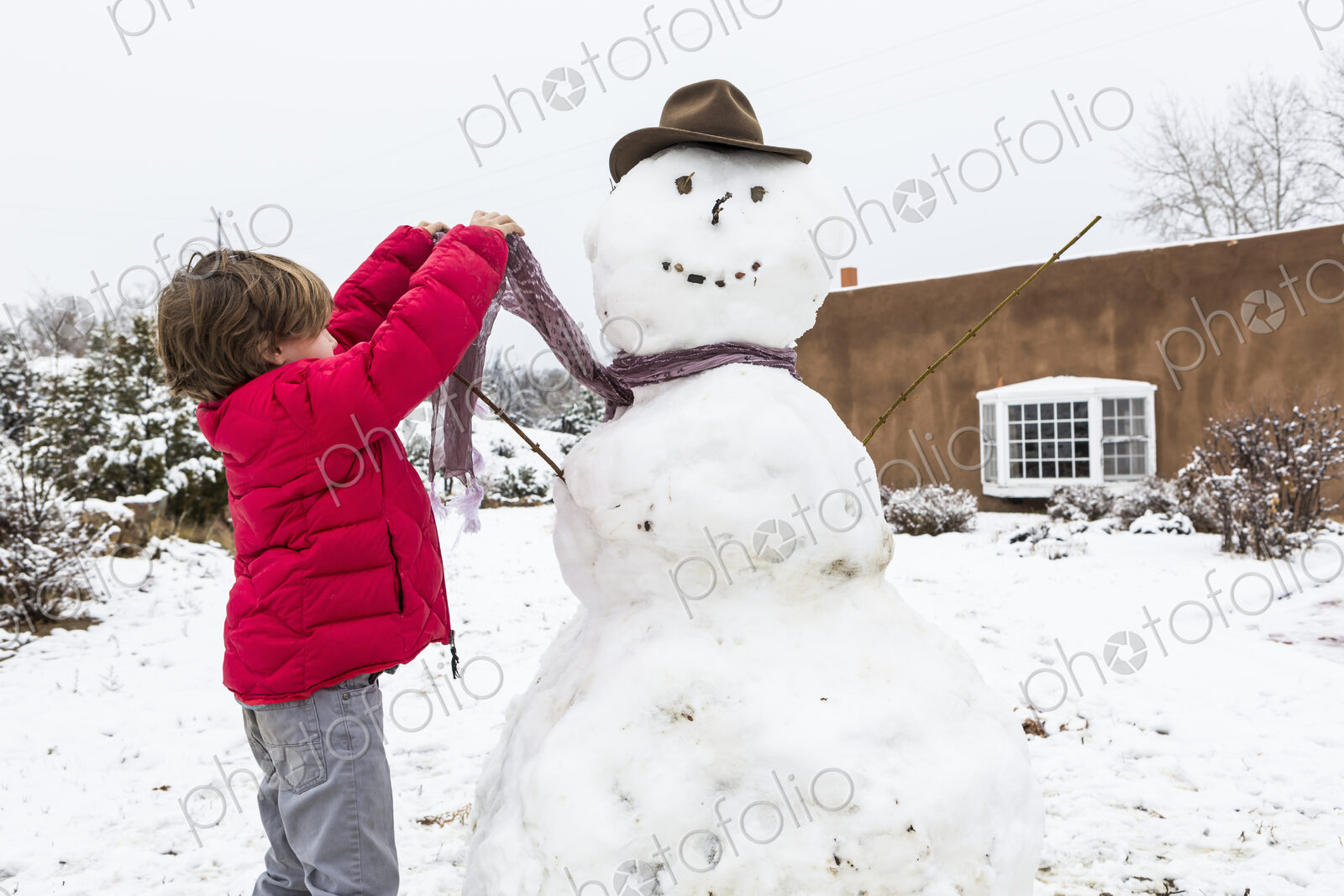 A six year old boy building a snowman