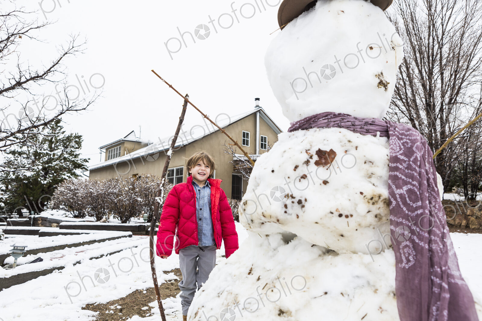 A six year old boy building a snowman
