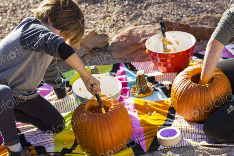 A six year old boy carving a pumpkin at Halloween.