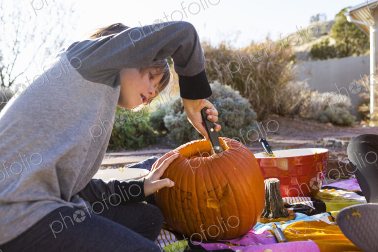 A six year old boy carving a pumpkin at Halloween.