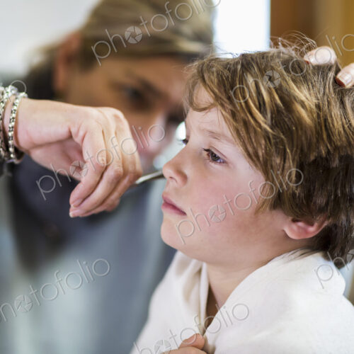 A six year old boy getting his hair cut at home by his mother A six year old boy getting his hair cut at home by his mother