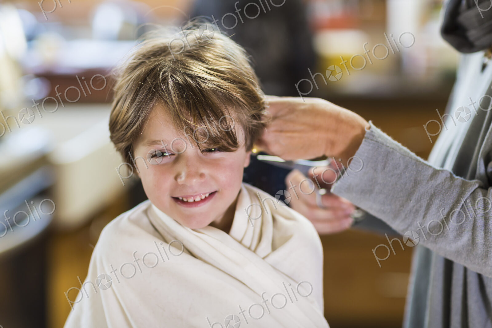 A six year old boy getting his hair cut at home by his mother